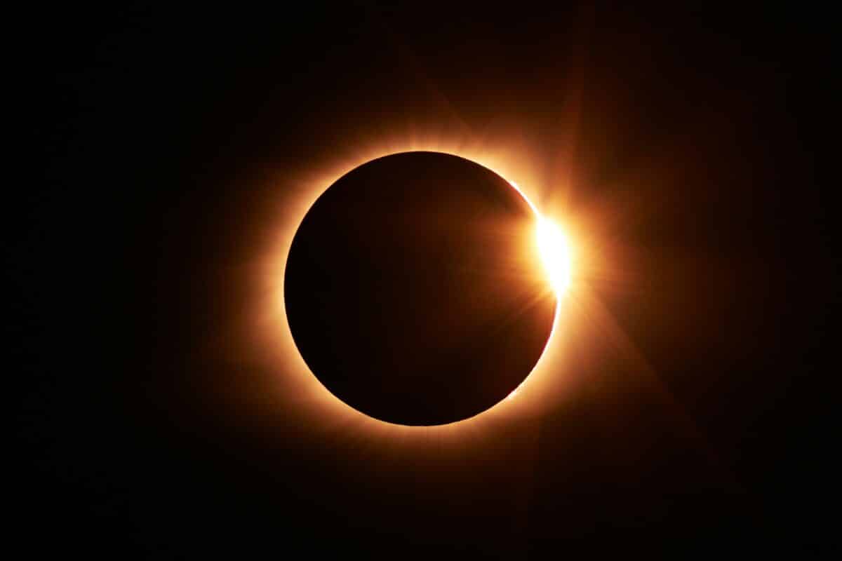 total eclipse of the sun is a ring of orange light that is dark in the center in a dark sky